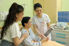 A medical worker at the University Medical Centre Ho Chi Minh City use tablets to update and share information with a patient. (Photo: VNA)